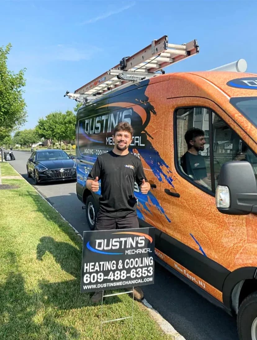 A Dustin's technician giving a thumbs up next to the company van and a New Egypt, NJ yard sign