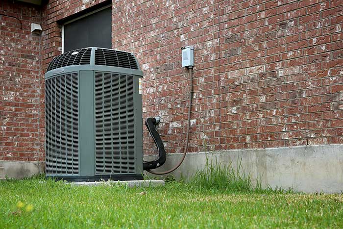 Outdoor air conditioning unit installed near a brick wall